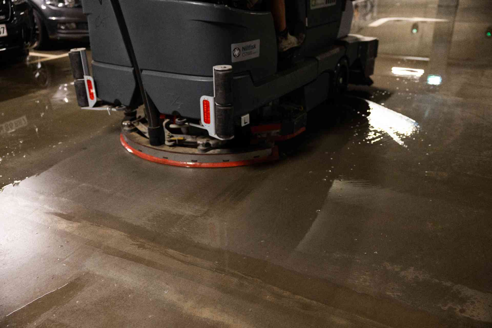 Rengøring af betongulv med gulvvaskemaskine i parkeringsgarage.