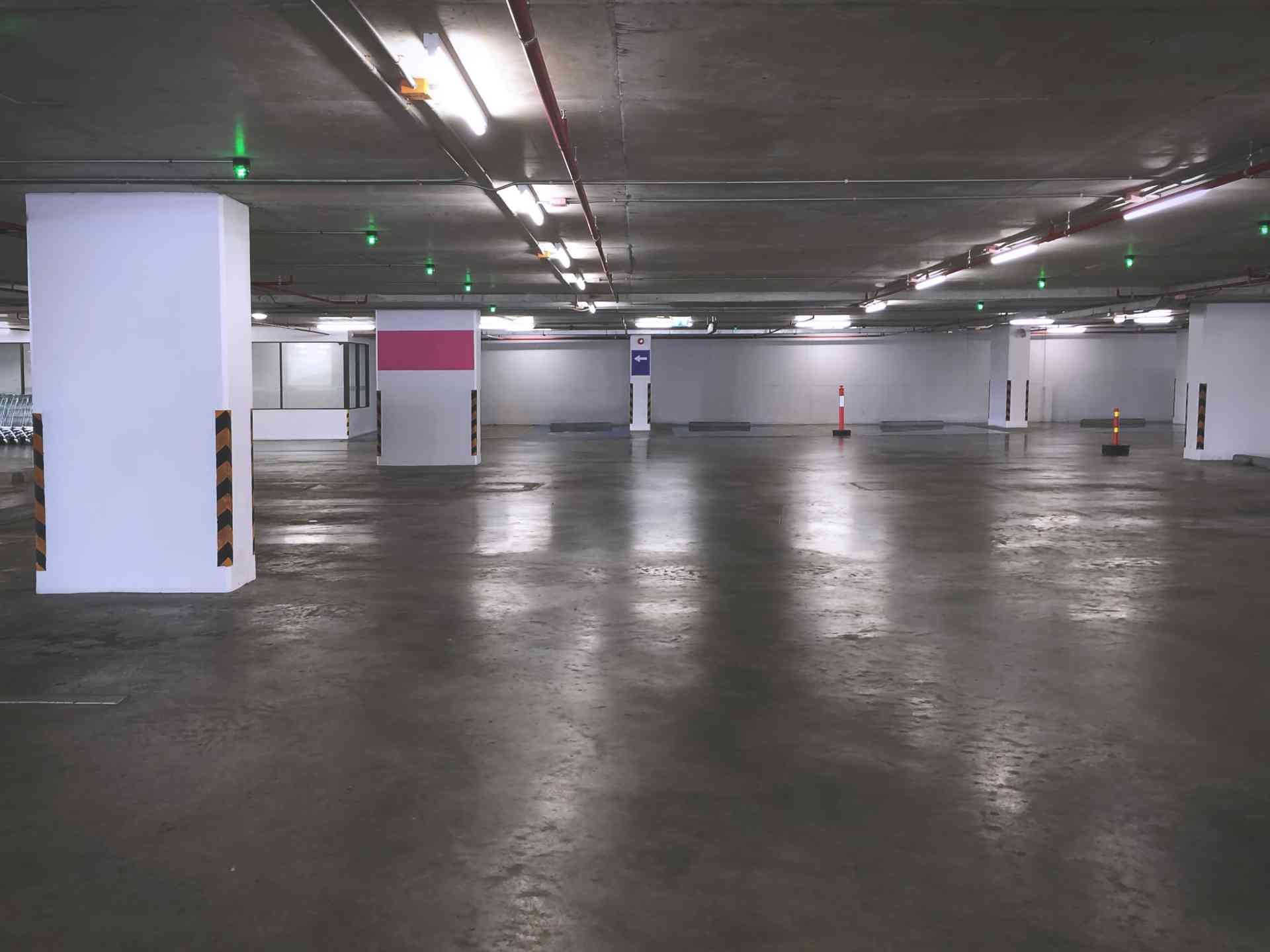 Rengøring af parkeringskælder med glat betonoverflade og belysning.